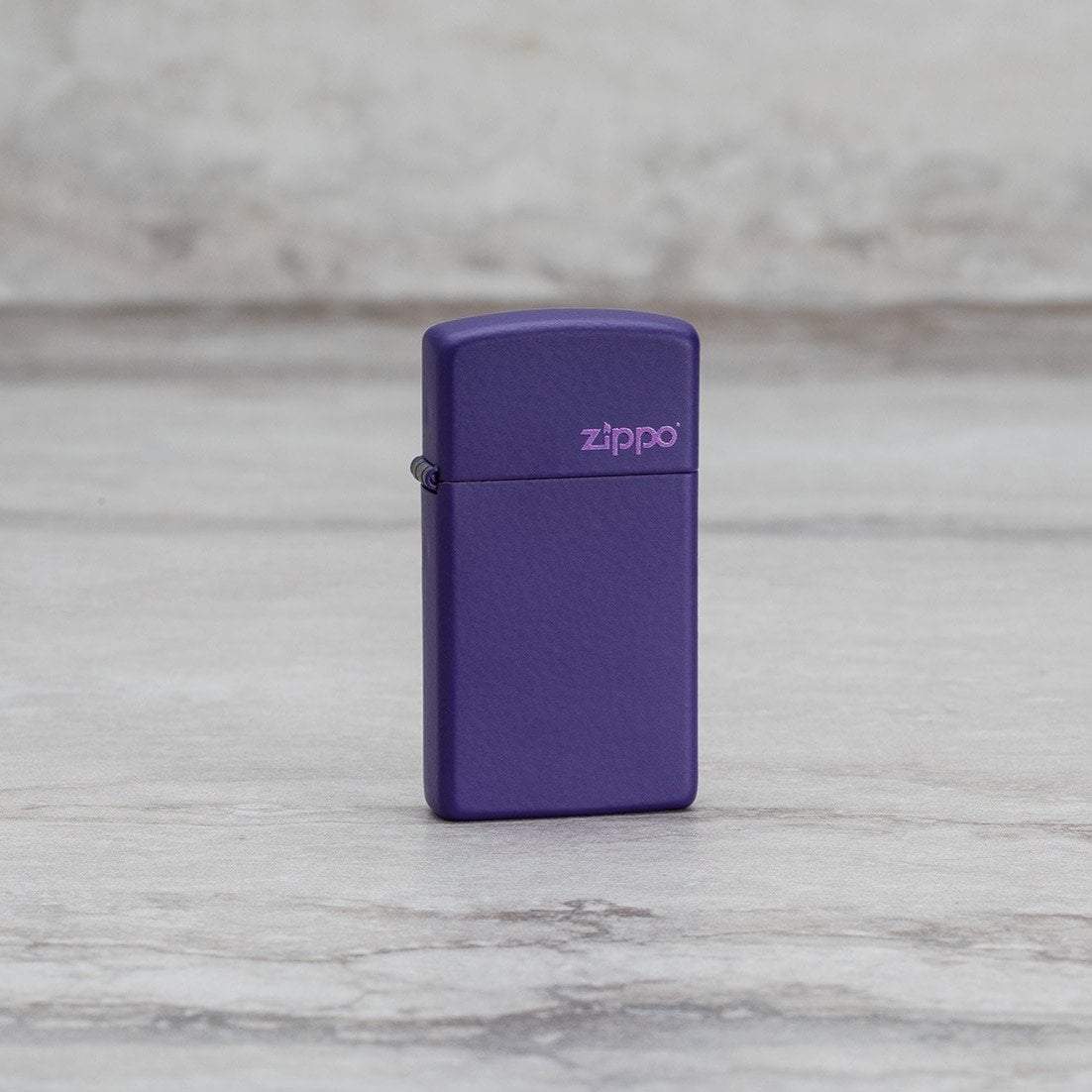 Lifestyle image of Slim?« Purple Matte Zippo Logo Windproof Lighter standing on a marble surface