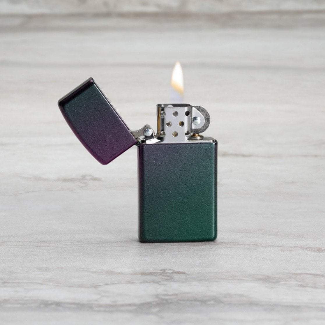 Lifestyle image of Slim?« Iridescent Windproof Lighter with its lid open and lit