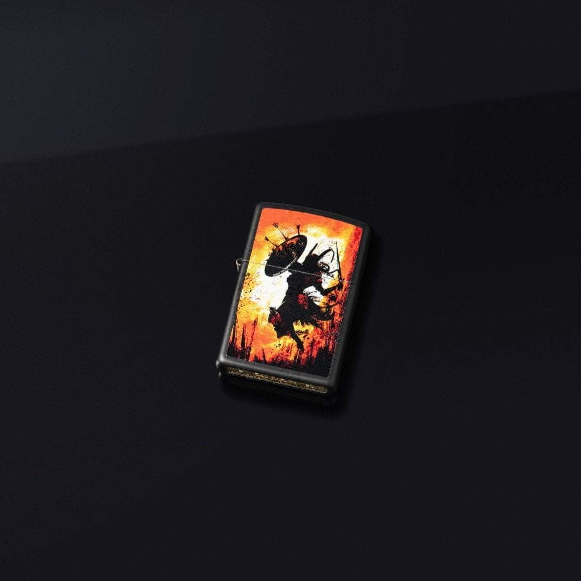 Lifestyle image of Warrior Design Black Matte Windproof Lighter laying on a black surface