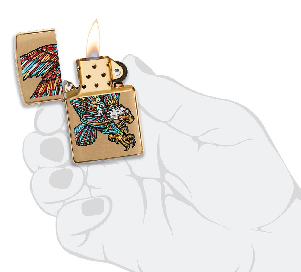 Tattoo Eagle Design Brushed Brass Windproof Lighter lit in hand.